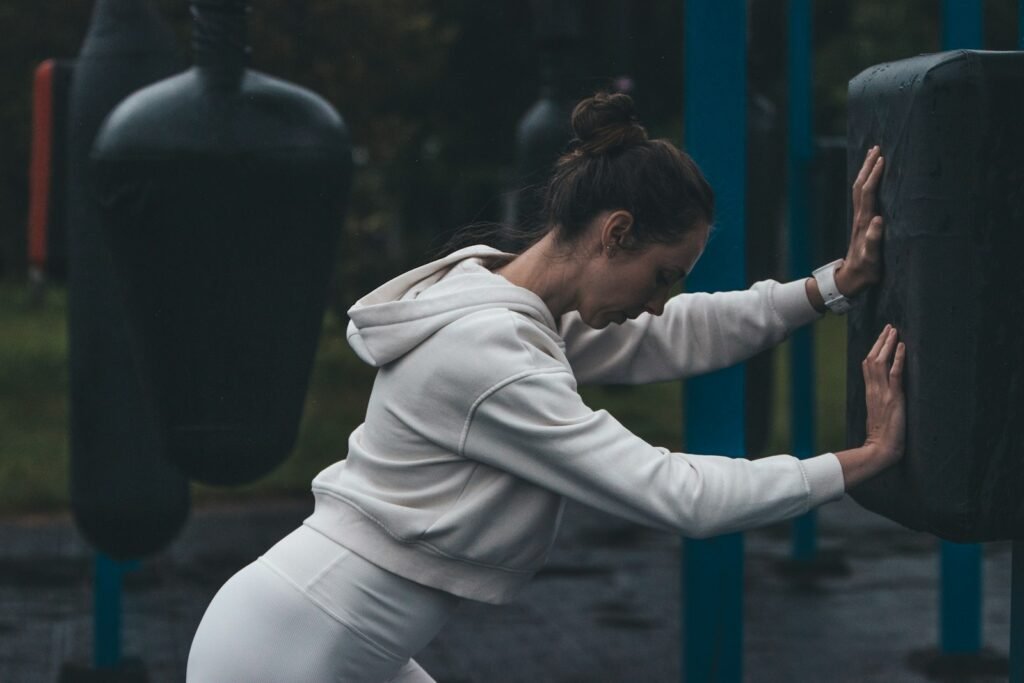 A woman stretches at an outdoor boxing gym.